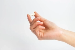 A hand holding a capsule