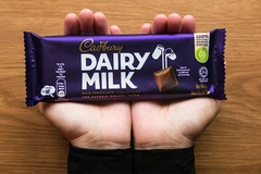 Hands holding Cadbury chocolate bar.