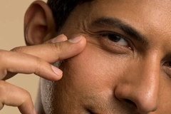 Image A man touching his eye.