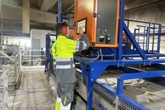 Image A person in a yellow jacket working on a machine
