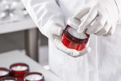 Image Hands wearing gloves opening a pot of cream.