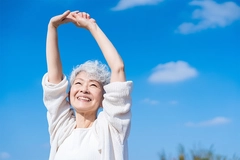 Image Old happy woman stretches arms in the air outdoors