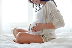Image pregnant woman sitting on bed