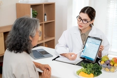 Image nutritionist showing AI meal plan on tablet to senior patient