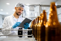man inspecting glass bottle line