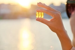 Image woman holding vitamin D supplements in the sun