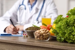 Image Young female nutritionist with clipboard and healthy food writing diet plan in office
