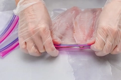 Image A person holding a plastic bag of fish