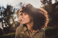 Image A woman with nice hair smiles in the sun.