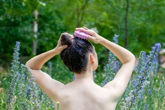 Image woman massages scalp surrounded by flowers