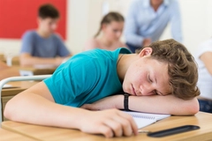 Image Tired student fell asleep on desk in the class