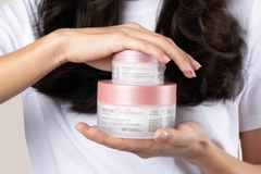 A person holding two jars of cream