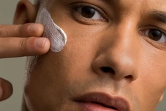 Image A man swiping lotion on his cheek.