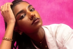 Woman with a nose ring resting on arm against pink background