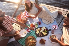 two girls and a guy picnic on port above ocean