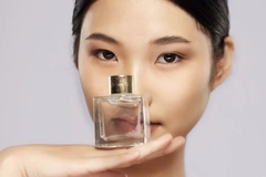 Image Woman holding a bottle of perfume in front of her face