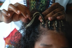 Image Hands braiding a young girls hair with blonde extensions.