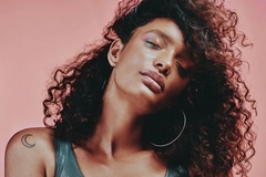 Image A woman with curly hair tilting her head with her eyes closed.