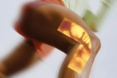 Image Abstract close-up of a bent leg with translucent amber geometric overlay and soft red and green motion blur.
