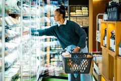 Image woman reaching for something in supermarket fridge