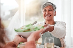 Image Middle aged woman hands over salad bowl to girl