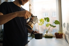 Image Man pouring coffee from pot into cup.