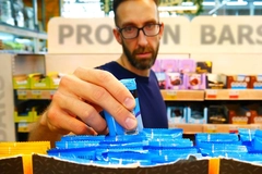 Image man picking up protein bar from supermarket aisle