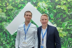 Image Two men standing in front of a sign