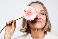 Image middle aged woman holding a flower in front of her face