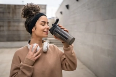 Image woman drinking protein shake outside