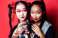 Image Two women with Chinese makeup and traditional wear against a red backdrop