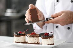 Image Chef piping chocolate onto chocolate-based desserts.