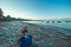 woman sits on beach surrounded by plastic packaging