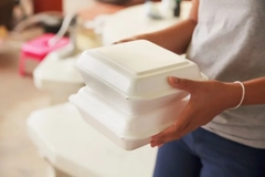 Image A person holding a stack of styrofoam boxes