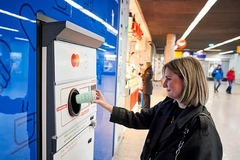 A person putting a cup into a vending machine