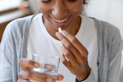 Woman taking supplement capsules