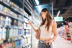 Image Young Asian consumer shopping for dairy products in supermarket.