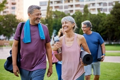 4 middle aged people carrying mats and waterbottle after workout