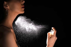 Image Woman spraying luxury perfume on black background.