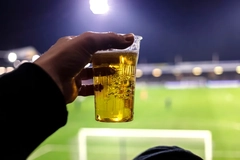 Image A hand holding a glass of beer in a stadium