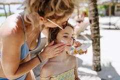 Image A mother putting sunscreen on her daughter.