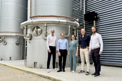 people standing in front of large bioreactor