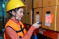 Image A person wearing a hard hat and safety vest scanning a bar code