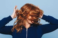 Image Woman shaking her hair against a blue backdrop