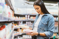 young woman in supermarket holding two bottles