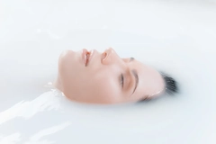 Image A woman's face coming out of milky water.