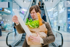 Image Man looking at food prices on a receipt in the grocery store.