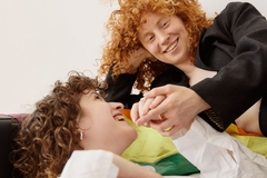 Image two women hold hands next to rainbow flag