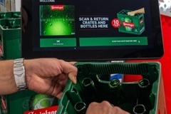 Image A person holding a green crate with bottles in it