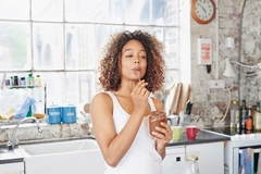 Image Woman eating chocolate paste in kitchen.